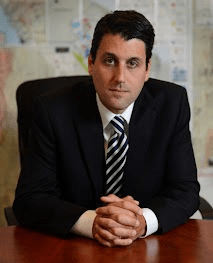 Picture of Marin Katusa at his desk with maps posted on the wall behind him
